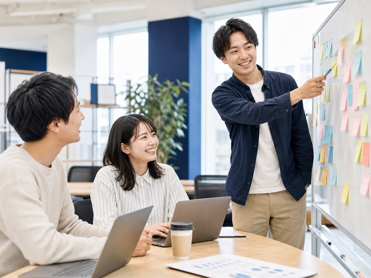 自然光の入るオフィスでホワイトボードを囲む笑顔のチームミーティング